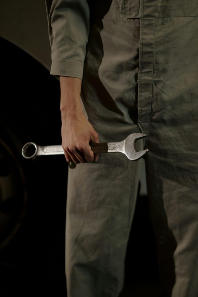 pexels-photo-7006695-7006695 Close-up of an auto mechanic holding a wrench in a workshop setting.